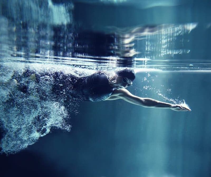 A competitive female swimming underwater | One Pool by Aqua Platinum